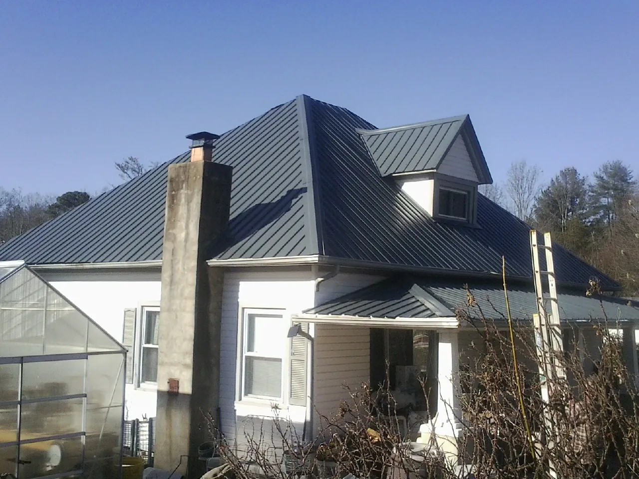 Dark blue standing seam metal roof on a white farmhouse with dormer — Slate & Tile Roof Repair by Roofing Brothers in Frankenmuth