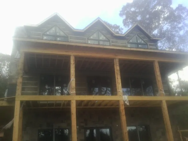 Dormers and porch framing on a large log home under construction — Roof Coating work by our crew in Frankenmuth