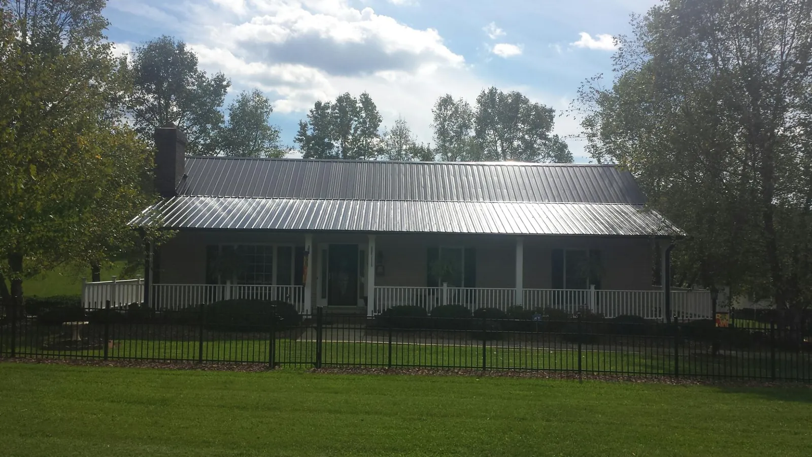 Gray metal roof on a brick ranch with a full width front porch — Gutter Guard Installation work by our crew in Frankenmuth
