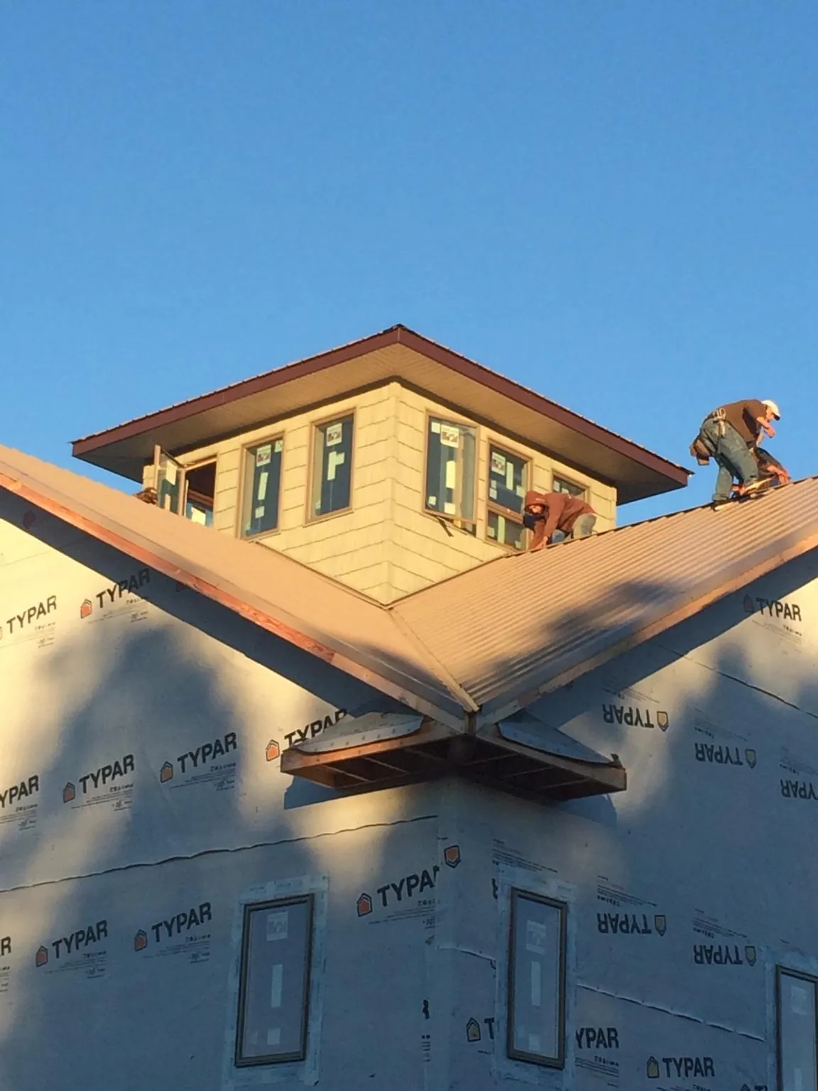 Roofers working around a rooftop cupola on a new metal roof at sunset — Roof Waterproofing in Frankenmuth by Roofing Brothers